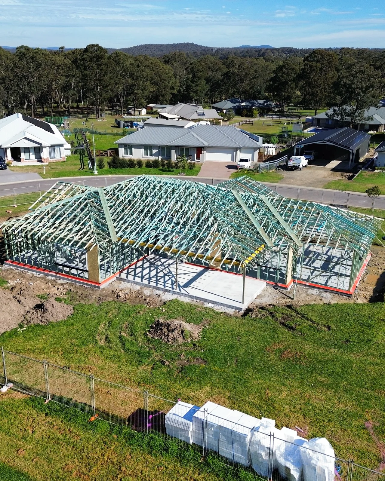 Aerial view of wall framing and roof trusses on a residential building site.